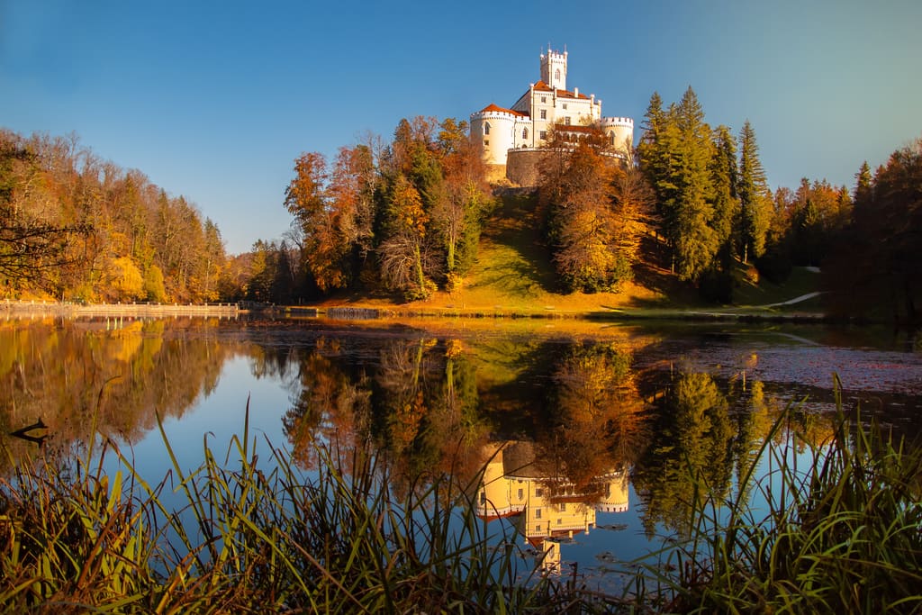 Trakošćan Castle on its hill above the lake, in autumn colours