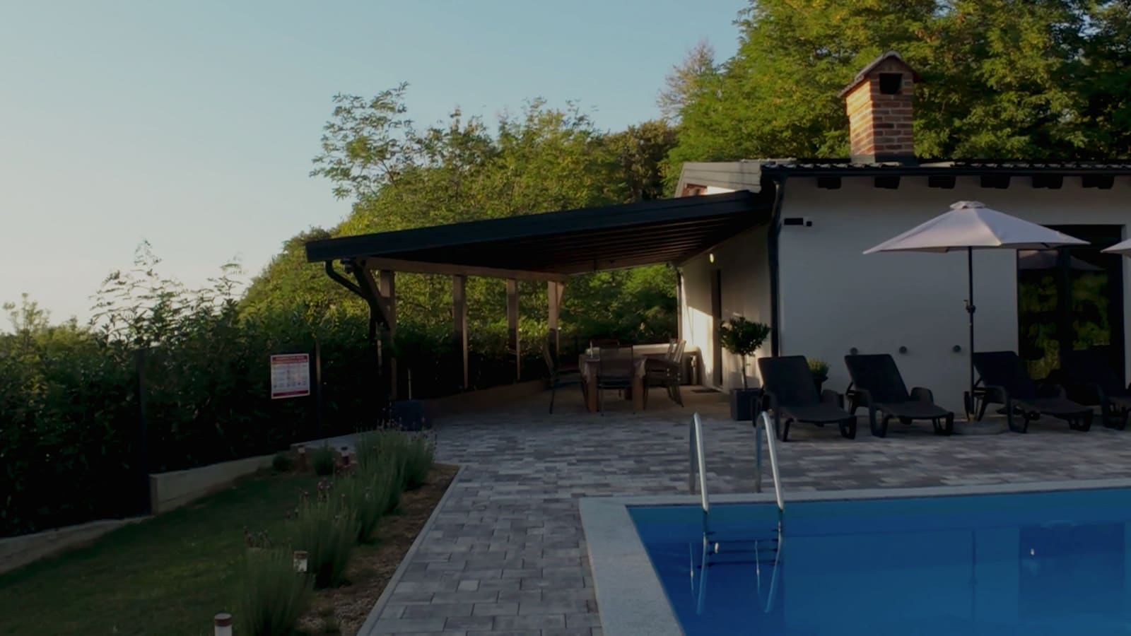 The house with its pergola, loungers and pool in the late afternoon